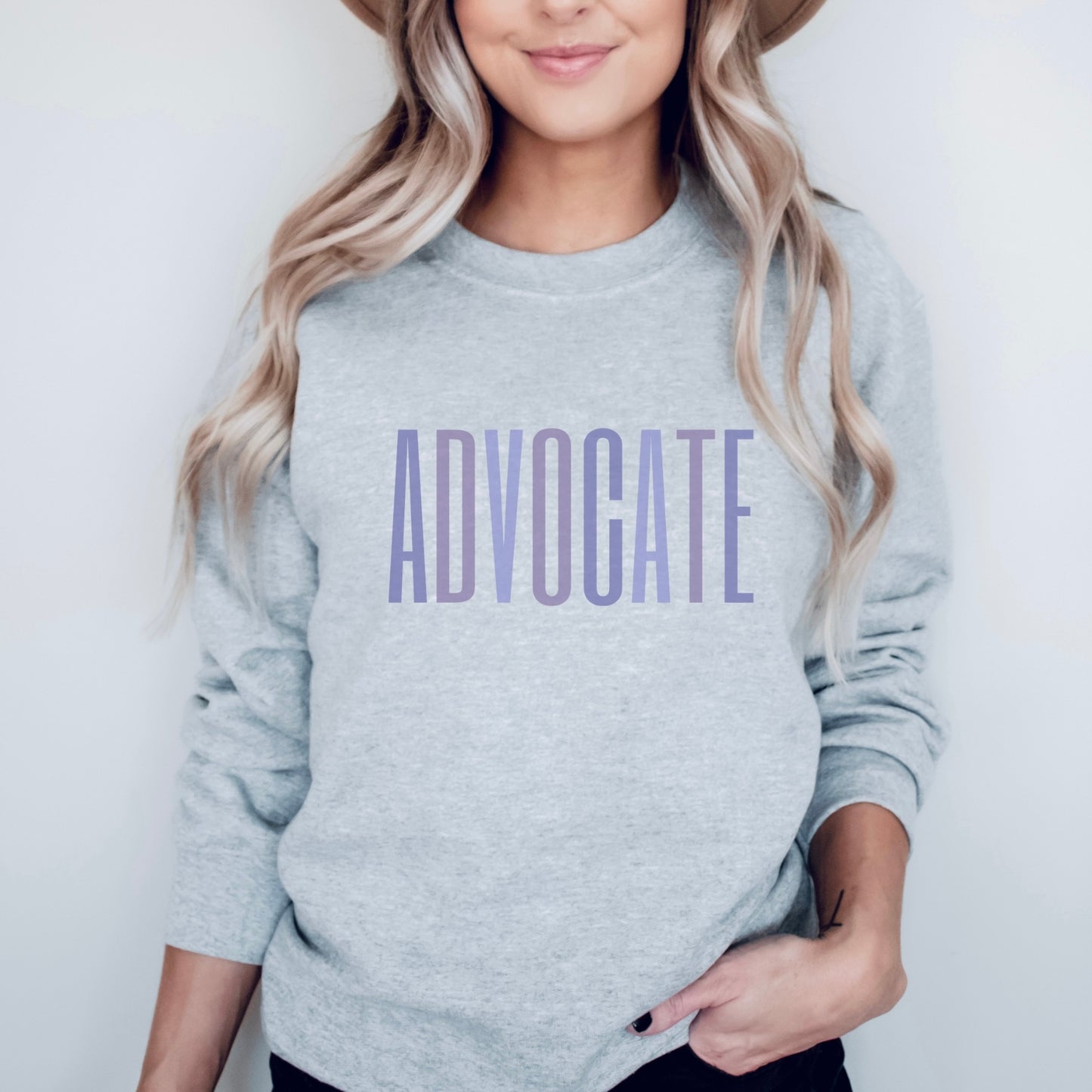 Crewneck sweatshirt with a powerful "ADVOCATE" wordmark emblazoned across the chest in varying shades of purple, symbolizing the strength and unity of domestic violence advocates. The gradient effect from deep violet to lavender adds an eye-catching touch, making this sweater a visually compelling tribute to your commitment to ending domestic abuse.