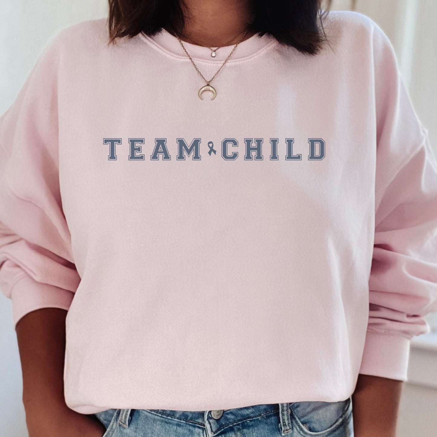 Our exclusive sweatshirt has ‘Team Child’ on the front in a bold font with the blue child abuse awareness ribbon between the words. This impactful phrase encapsulates the essence of your commitment to safeguarding children and promoting their well-being. Perfect for child advocates, champions of children’s mental health, and for Child Abuse Awareness and Prevention Month (CAPM)