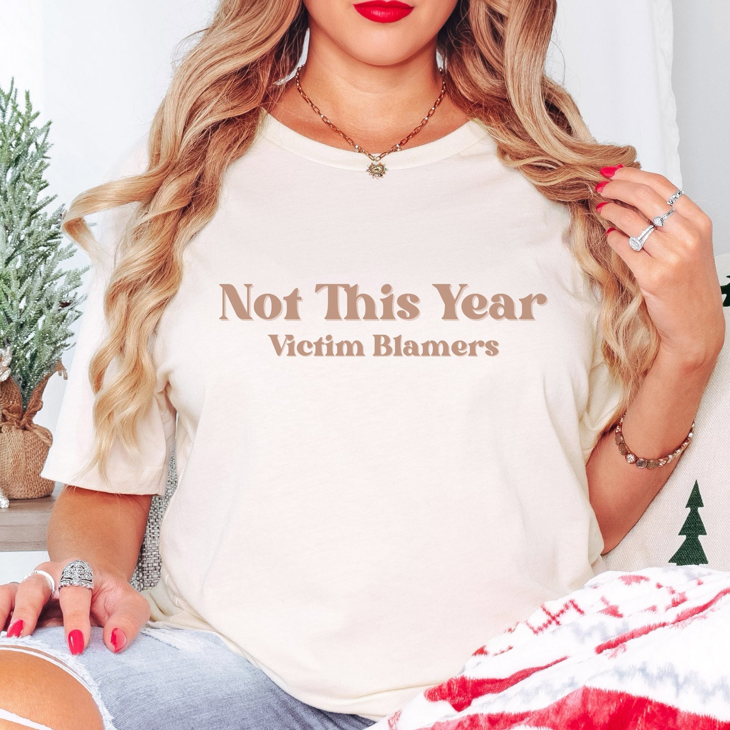 The front of the sweatshirt proudly displays the phrase "Not This Year Victim Blamers" in a bold and eye-catching font. This message serves as a reminder that we reject victim-blaming and support those who have faced injustice.