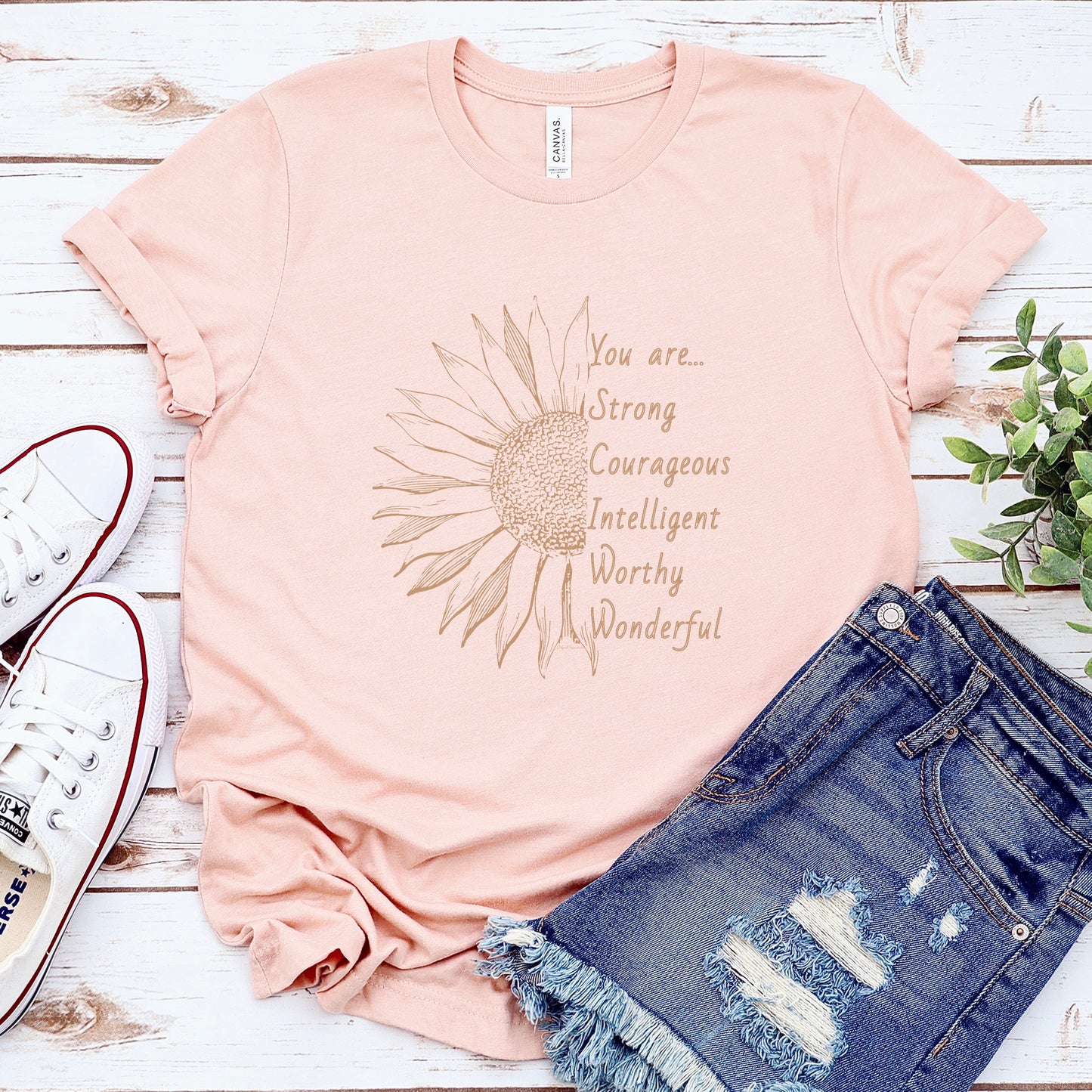 This thoughtfully designed shirt features a vibrant sunflower, symbolizing resilience and growth, accompanied by the powerful mantra: "You are strong, courageous, intelligent, worthy, and wonderful."