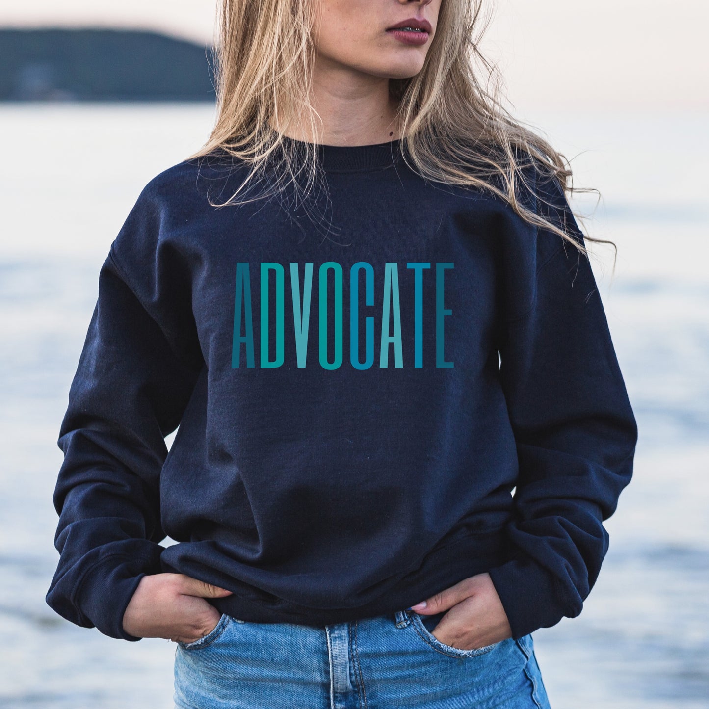 The front of the sweatshirt proudly displays the word ADVOCATE in a bold and eye catching font in varying shades of blue which is the color of child advocacy. It is a wearable symbol of your dedication to a world where all children are loved, cherished, and protected.