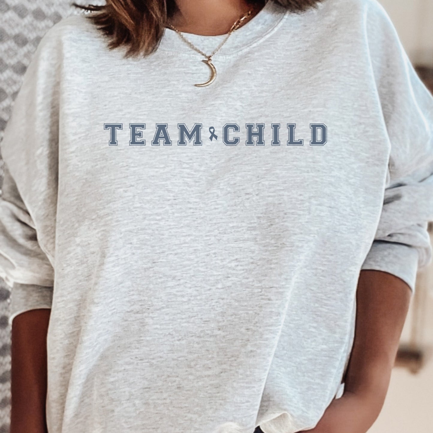 Our exclusive sweatshirt has ‘Team Child’ on the front in a bold font with the blue child abuse awareness ribbon between the words. This impactful phrase encapsulates the essence of your commitment to safeguarding children and promoting their well-being. Perfect for child advocates, champions of children’s mental health, and for Child Abuse Awareness and Prevention Month (CAPM)