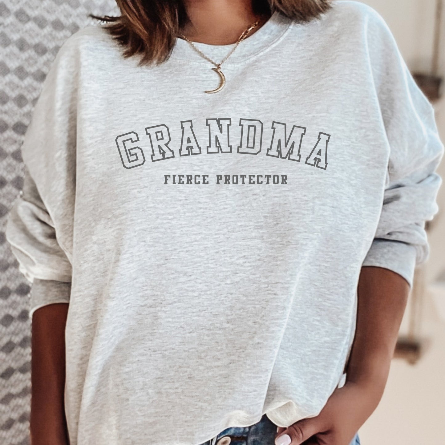 The front of the sweatshirt proudly displays the phrase Grandma Fierce Protector in a bold and eye catching font. This message serves as a reminder that we reject victim blaming and support those who have faced injustice. Your grandma can wear her strength proudly, embracing both comfort and empowerment.