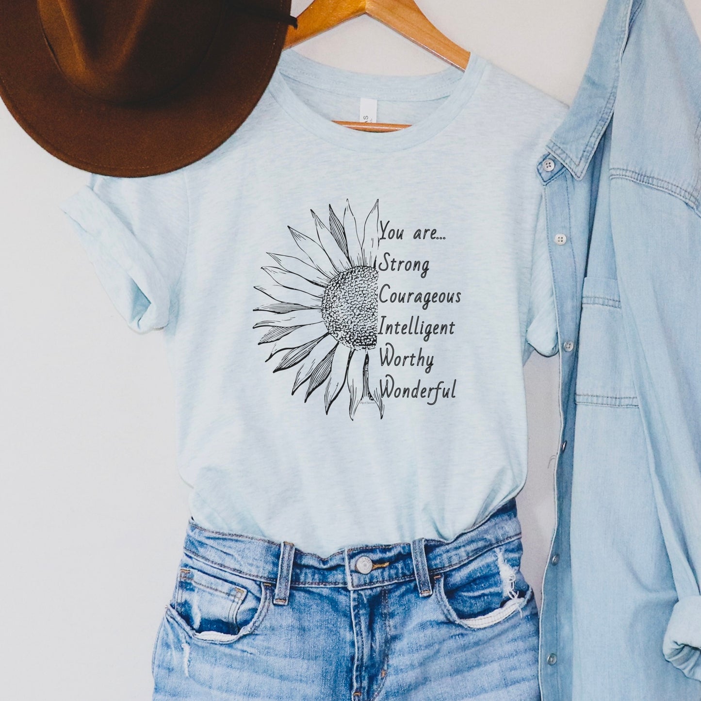 This thoughtfully designed shirt features a vibrant sunflower, symbolizing resilience and growth, accompanied by the powerful mantra: "You are strong, courageous, intelligent, worthy, and wonderful."