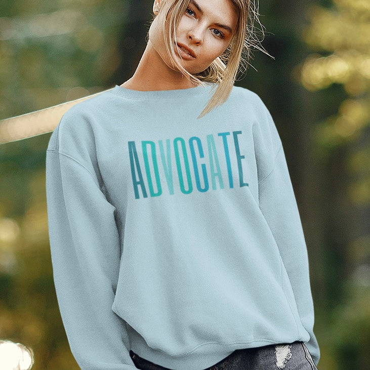 The front of the sweatshirt proudly displays the word ADVOCATE in a bold and eye catching font in varying shades of blue which is the color of child advocacy. It is a wearable symbol of your dedication to a world where all children are loved, cherished, and protected.
