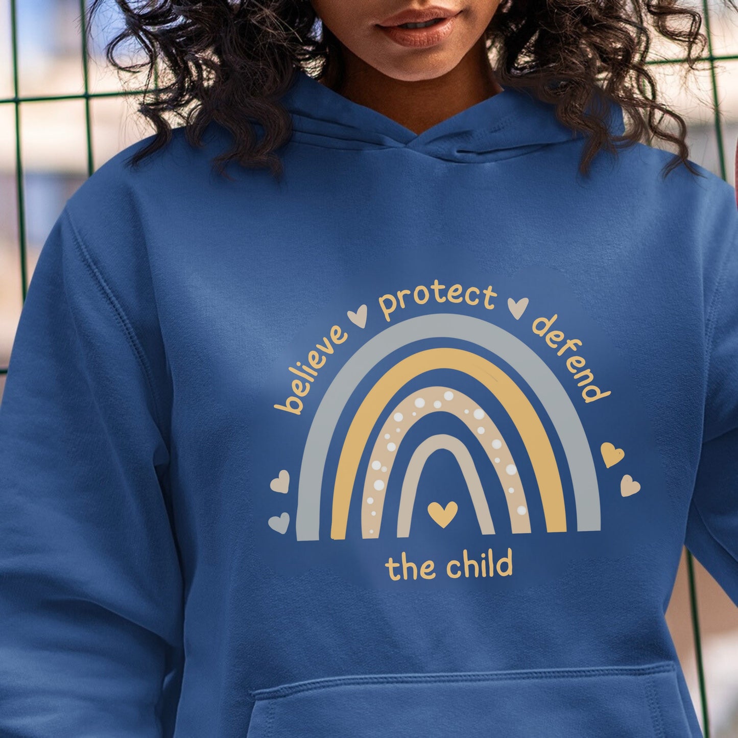 The front of the sweatshirt proudly displays a boho rainbow with the phrase "Believe Protect Defend The Child” in a whimsical and eye-catching font. A powerful message that underscores the importance of safeguarding children's rights and well-being.