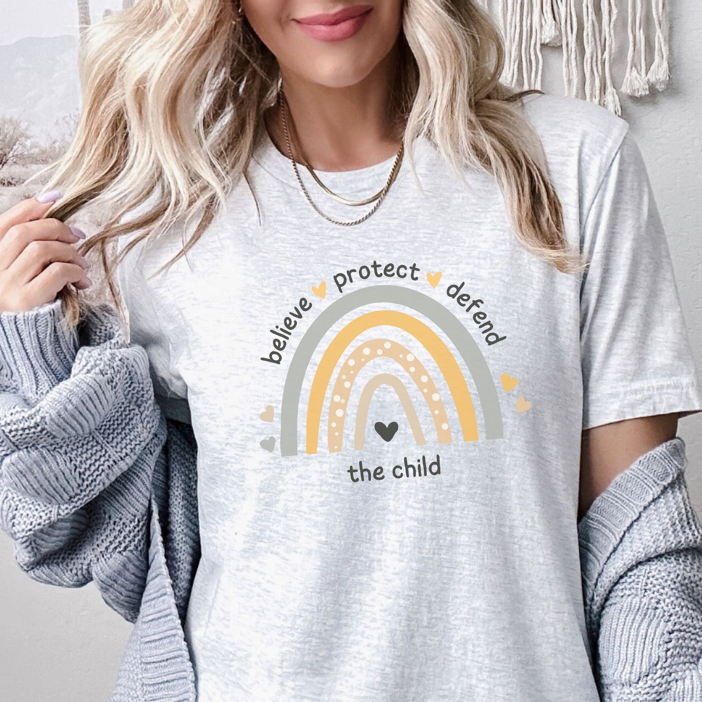 The front of the tee displays a boho rainbow with the phrase Believe Protect Defend The Child. A powerful message that underscores the importance of safeguarding children's rights and well being. Perfect for child advocates and Child Abuse Awareness and Prevention Month (CAAPM)