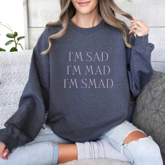 The front of the sweatshirt proudly displays the phrase "I’m Sad. I’m Mad. I’m Smad." in a bold and eye-catching font. The design is not just a fashion statement; it's a conversation starter that promotes mental health awareness and destigmatizes the spectrum of feelings we all experience.