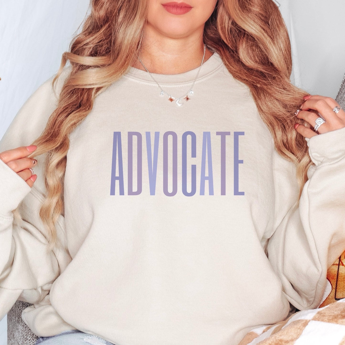 Crewneck sweatshirt with a powerful "ADVOCATE" wordmark emblazoned across the chest in varying shades of purple, symbolizing the strength and unity of domestic violence advocates. The gradient effect from deep violet to lavender adds an eye-catching touch, making this sweater a visually compelling tribute to your commitment to ending domestic abuse.