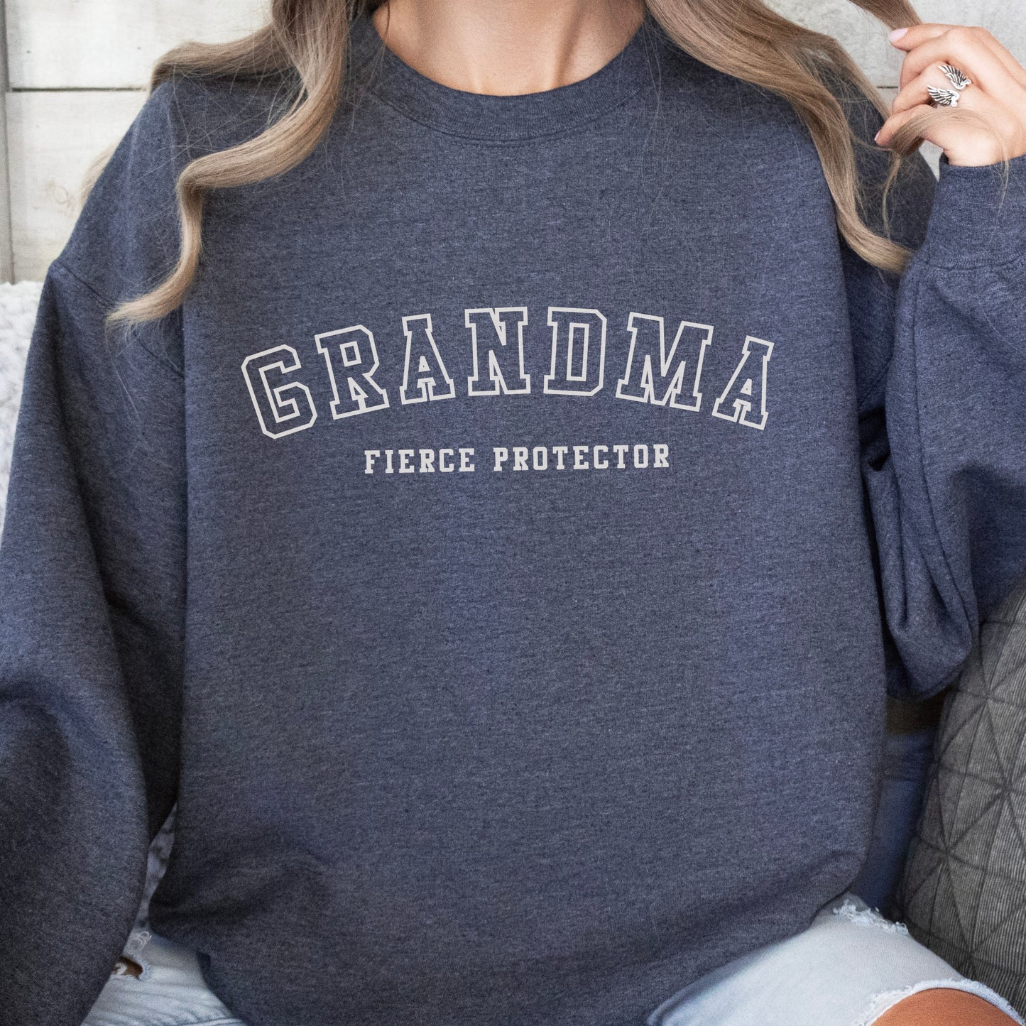 The front of the sweatshirt proudly displays the phrase Grandma Fierce Protector in a bold and eye catching font. This message serves as a reminder that we reject victim blaming and support those who have faced injustice. Your grandma can wear her strength proudly, embracing both comfort and empowerment.