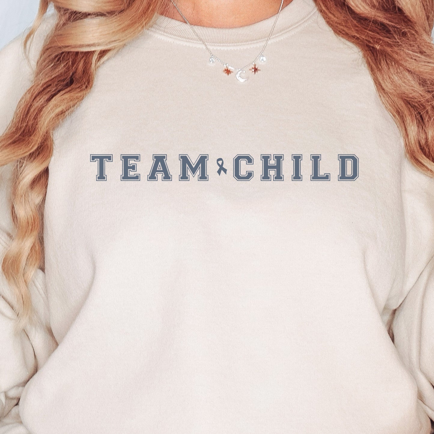 Our exclusive sweatshirt has ‘Team Child’ on the front in a bold font with the blue child abuse awareness ribbon between the words. This impactful phrase encapsulates the essence of your commitment to safeguarding children and promoting their well-being. Perfect for child advocates, champions of children’s mental health, and for Child Abuse Awareness and Prevention Month (CAPM)
