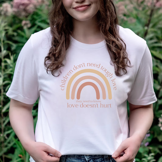 The front of the t-shirt has a beautiful boho rainbow that boldly declares, "Children don't need tough love, they need to know love doesn't hurt." It serves as a rallying cry for advocates, emphasizing the importance of fostering environments where love is synonymous with safety and support. Perfect for child advocates, family advocates, and Child Abuse Awareness and Prevention Month CAPM