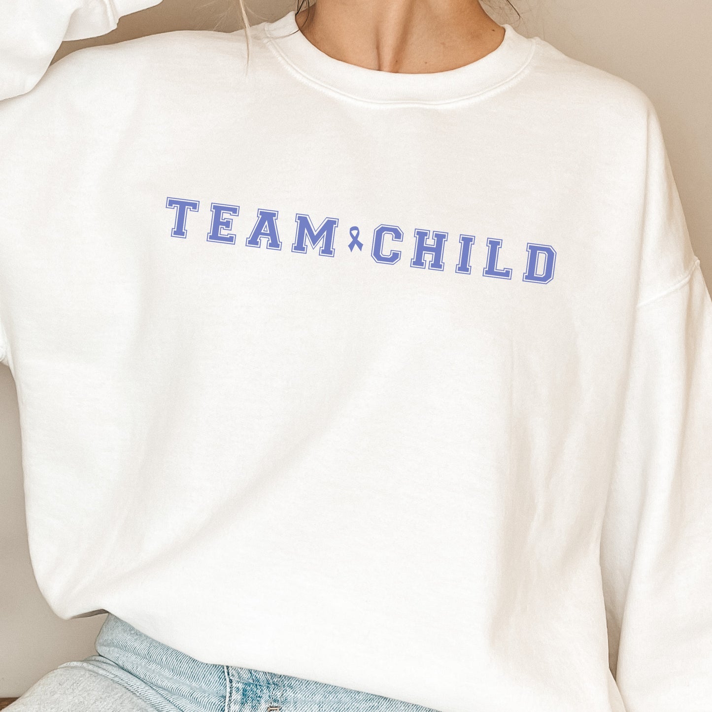 Our exclusive sweatshirt has ‘Team Child’ on the front in a bold font with the blue child abuse awareness ribbon between the words. This impactful phrase encapsulates the essence of your commitment to safeguarding children and promoting their well-being. Perfect for child advocates, champions of children’s mental health, and for Child Abuse Awareness and Prevention Month (CAPM)