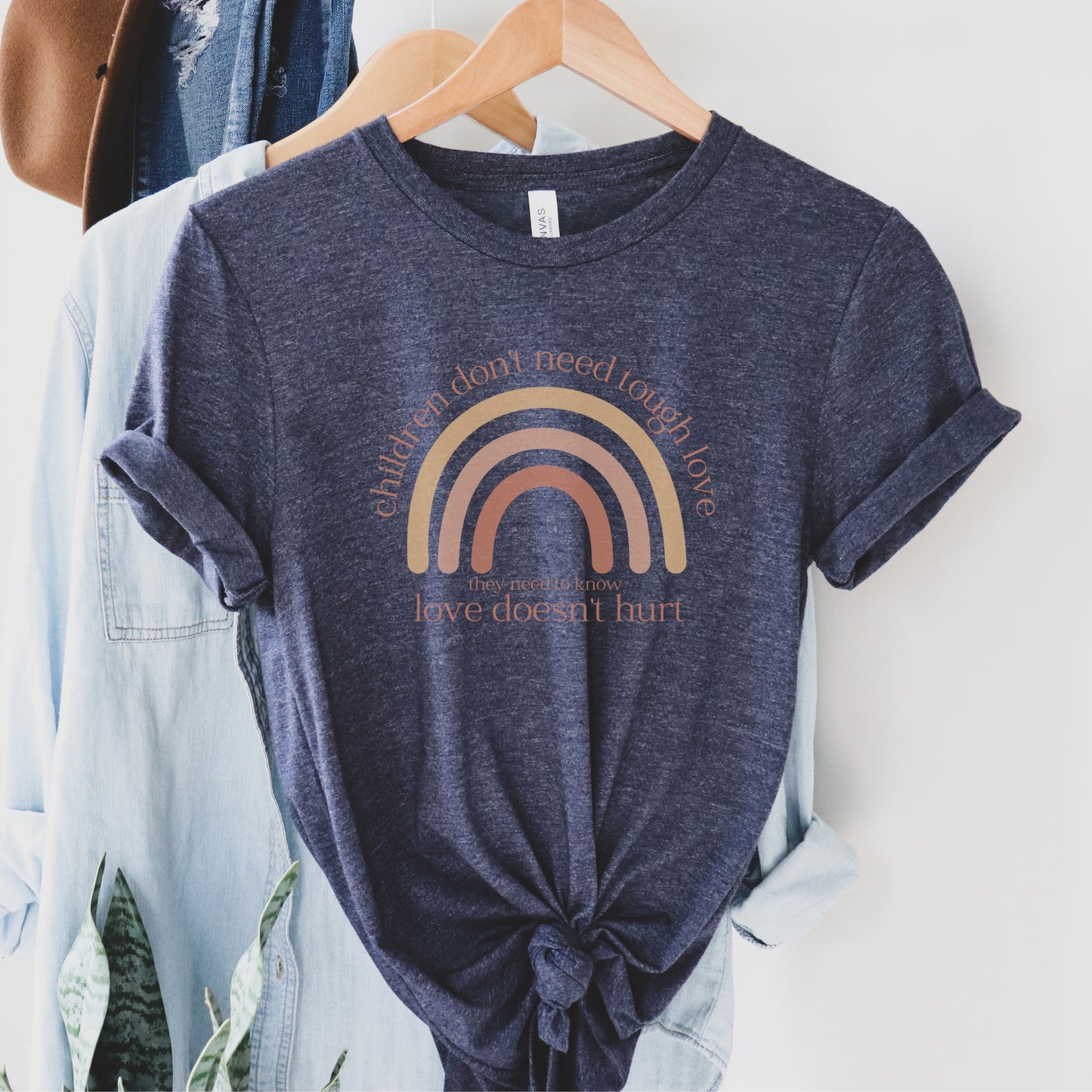 The front of the t-shirt has a beautiful boho rainbow that boldly declares, "Children don't need tough love, they need to know love doesn't hurt." It serves as a rallying cry for advocates, emphasizing the importance of fostering environments where love is synonymous with safety and support. Perfect for child advocates, family advocates, and Child Abuse Awareness and Prevention Month CAPM