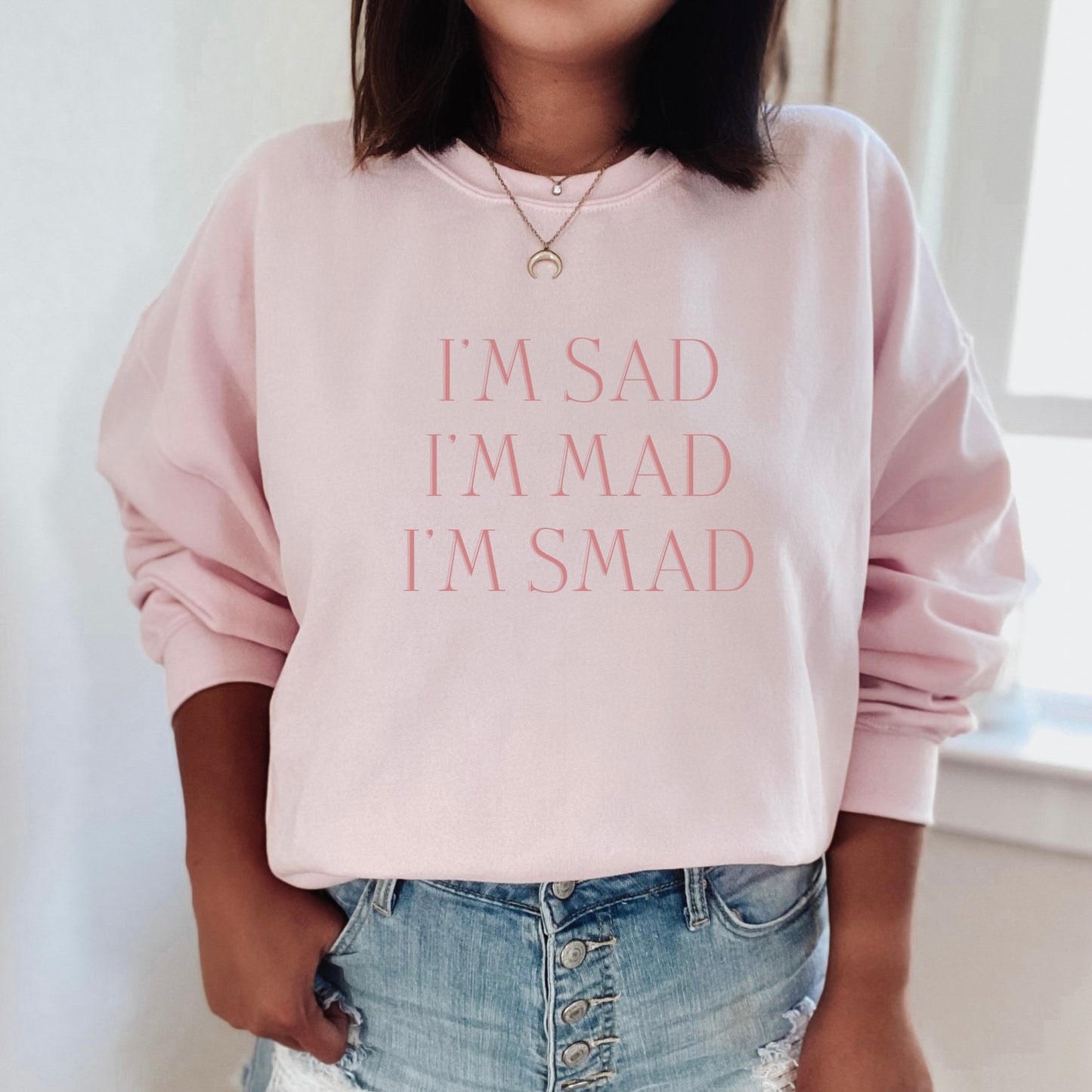 The front of the sweatshirt proudly displays the phrase "I’m Sad. I’m Mad. I’m Smad." in a bold and eye-catching font. The design is not just a fashion statement; it's a conversation starter that promotes mental health awareness and destigmatizes the spectrum of feelings we all experience.
