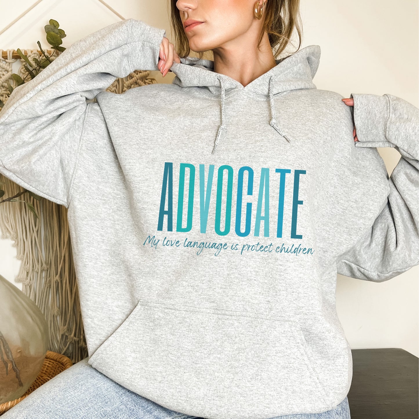 Front and center of this hooded sweatshirt, the bold message declares, "ADVOCATE: my love language is protect children." Artfully designed in varying shades of blue, this impactful phrase encapsulates the essence of your commitment to safeguarding children and promoting their well-being. Perfect for child advocates, champions of children’s mental health, and for Child Abuse Awareness and Prevention Month