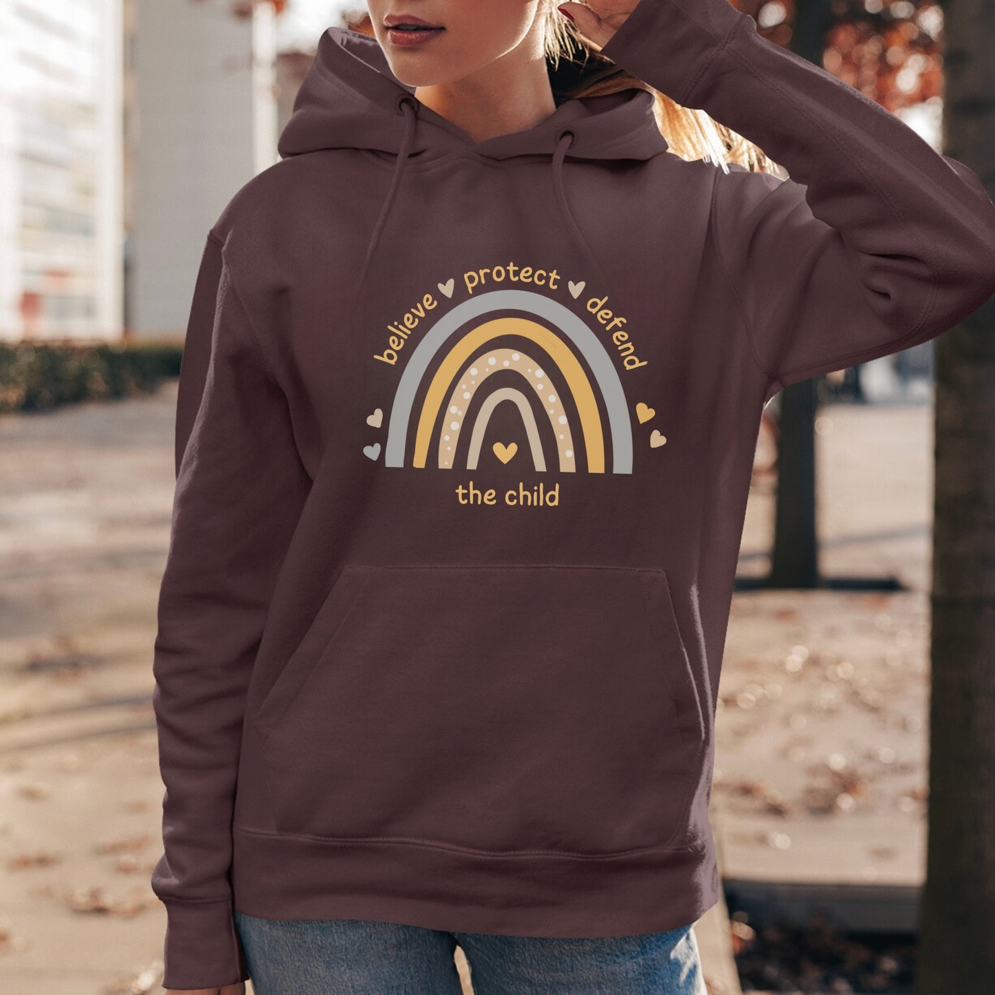 The front of the sweatshirt proudly displays a boho rainbow with the phrase "Believe Protect Defend The Child” in a whimsical and eye-catching font. A powerful message that underscores the importance of safeguarding children's rights and well-being.
