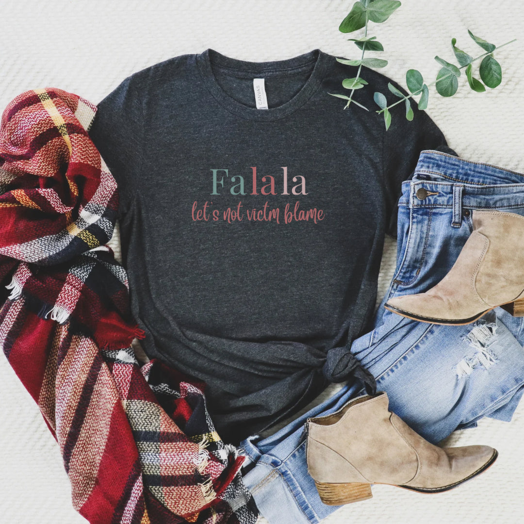 Empowerment-themed holiday T-shirt with festive trending colors design and the powerful statement 'Fa la la, Let's Not Victim Blame.' Ideal for advocates and survivors of abuse, this tee promotes empathy and awareness during the holiday season.