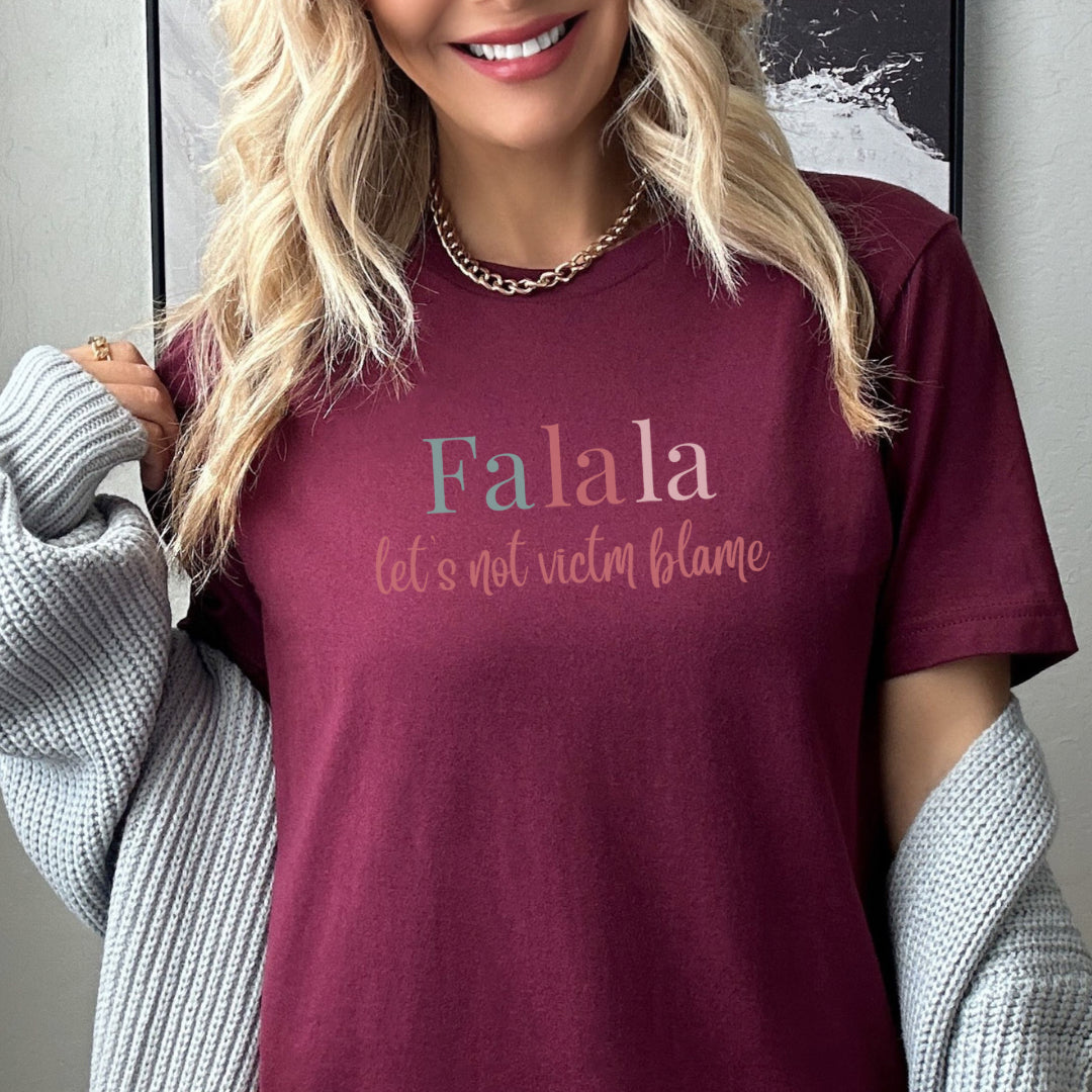 Empowerment-themed holiday T-shirt with festive trending colors design and the powerful statement 'Fa la la, Let's Not Victim Blame.' Ideal for advocates and survivors of abuse, this tee promotes empathy and awareness during the holiday season.