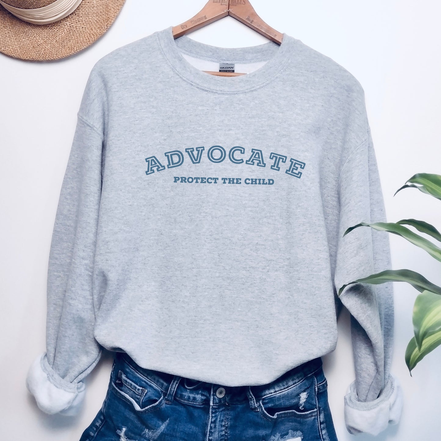 The front of the sweatshirt proudly displays the phrase "Advocate Protecct The Child" in a bold and eye-catching font. Crafted for child advocates and champions of children's mental health, and perfect for Child Abuse Awareness and Prevention Month!