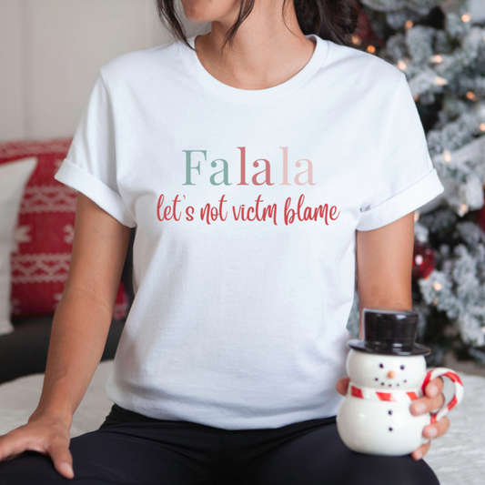 Empowerment-themed holiday T-shirt with festive trending colors design and the powerful statement 'Fa la la, Let's Not Victim Blame.' Ideal for advocates and survivors of abuse, this tee promotes empathy and awareness during the holiday season.