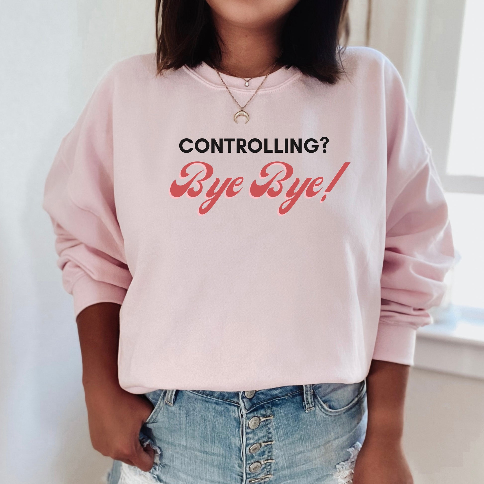 The front of the sweatshirt proudly displays the phrase "Controlling? Bye Bye!" in a bold and eye-catching font. This message serves as a reminder that love is not controlling. Tailored for domestic violence and teen dating violence advocates.