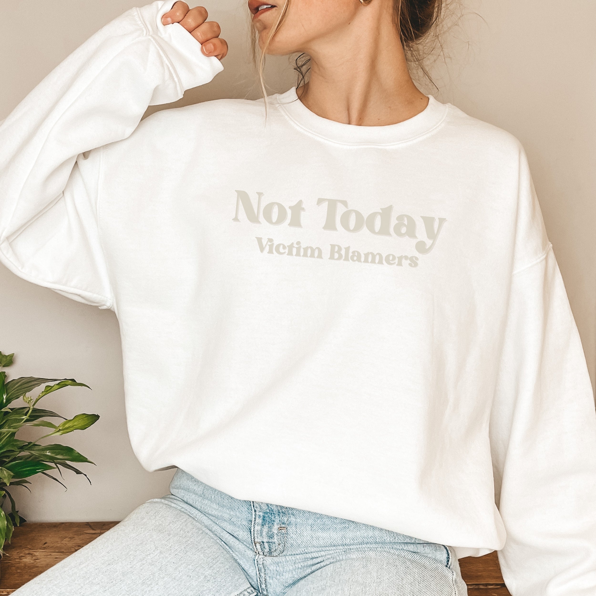 The front of the White sweatshirt proudly displays the phrase "Not Today Victim Blamers" in a Sand colored bold and eye-catching font. This message serves as a reminder that we reject victim-blaming and support those who have faced injustice.