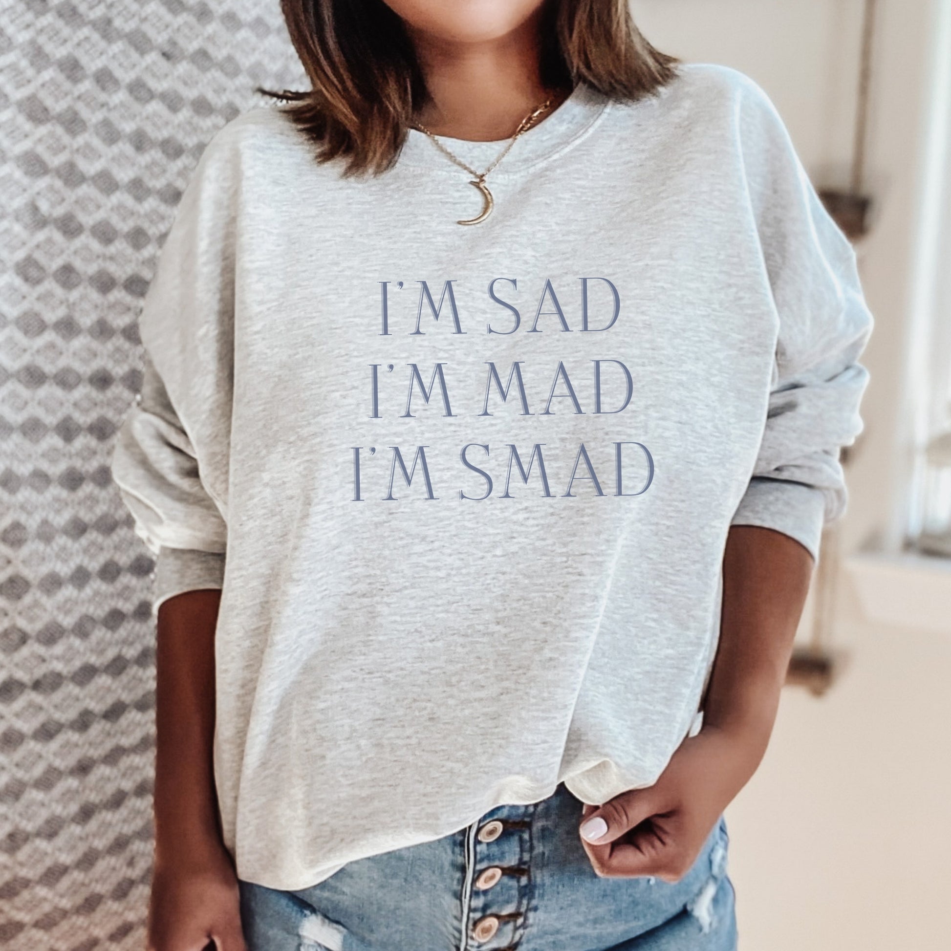 The front of the sweatshirt proudly displays the phrase "I’m Sad. I’m Mad. I’m Smad." in a bold and eye-catching font. The design is not just a fashion statement; it's a conversation starter that promotes mental health awareness and destigmatizes the spectrum of feelings we all experience.