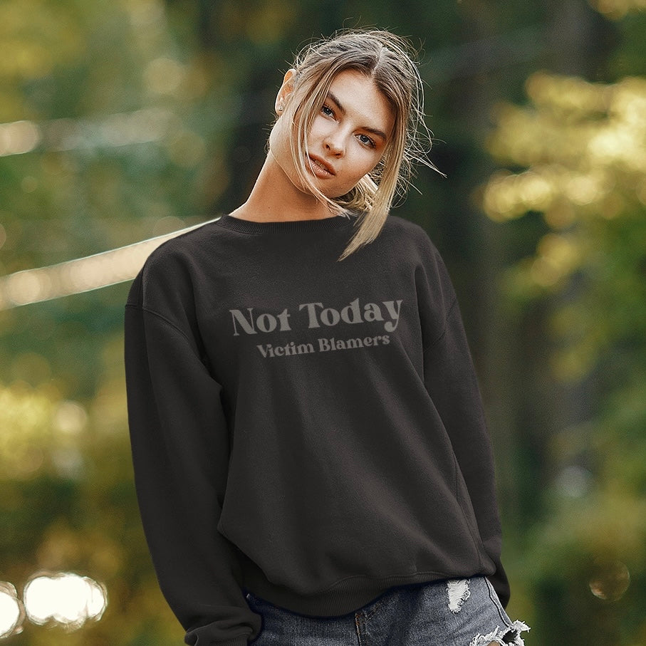 The front of the Black sweatshirt proudly displays the phrase "Not Today Victim Blamers" in a Light Black tone on tone bold and eye-catching font. This message serves as a reminder that we reject victim-blaming and support those who have faced injustice.