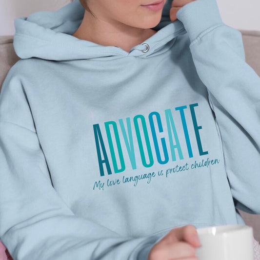 Front and center of this hooded sweatshirt, the bold message declares, "ADVOCATE: my love language is protect children." Artfully designed in varying shades of blue, this impactful phrase encapsulates the essence of your commitment to safeguarding children and promoting their well-being. Perfect for child advocates, champions of children’s mental health, and for Child Abuse Awareness and Prevention Month