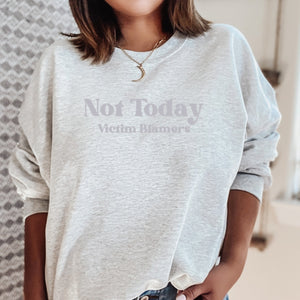 The front of the Ash sweatshirt proudly displays the phrase "Not Today Victim Blamers" in a Light Lavender bold and eye-catching font. This message serves as a reminder that we reject victim-blaming and support those who have faced injustice.