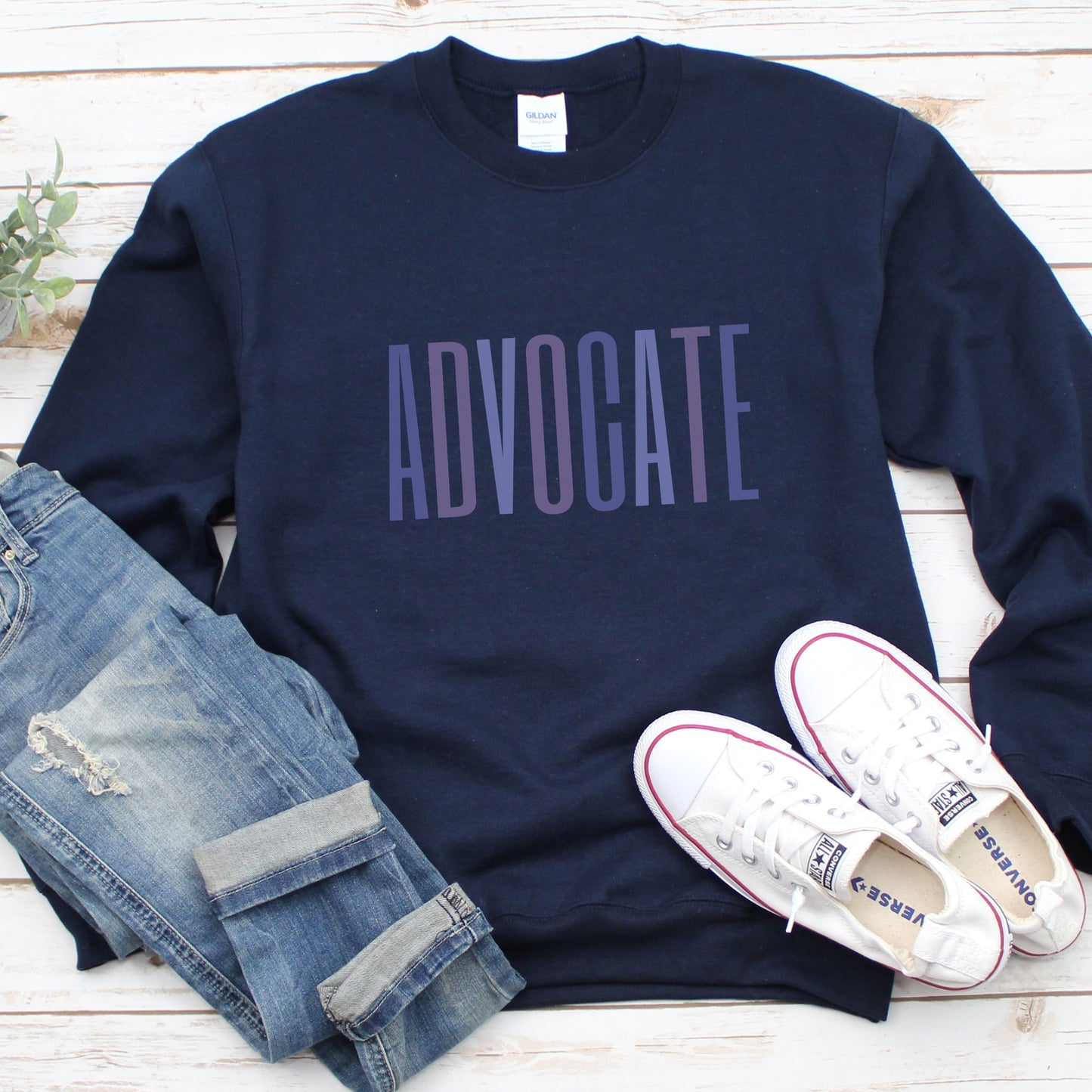 Crewneck sweatshirt with a powerful "ADVOCATE" wordmark emblazoned across the chest in varying shades of purple, symbolizing the strength and unity of domestic violence advocates. The gradient effect from deep violet to lavender adds an eye-catching touch, making this sweater a visually compelling tribute to your commitment to ending domestic abuse.