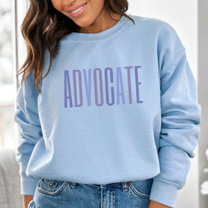Light Blue crewneck sweatshirt with a powerful  "ADVOCATE" wordmark emblazoned across the chest in varying shades of purple, symbolizing the strength and unity of domestic violence advocates. The gradient effect from deep violet to lavender adds an eye-catching touch, making this sweater a visually compelling tribute to your commitment to ending domestic abuse.