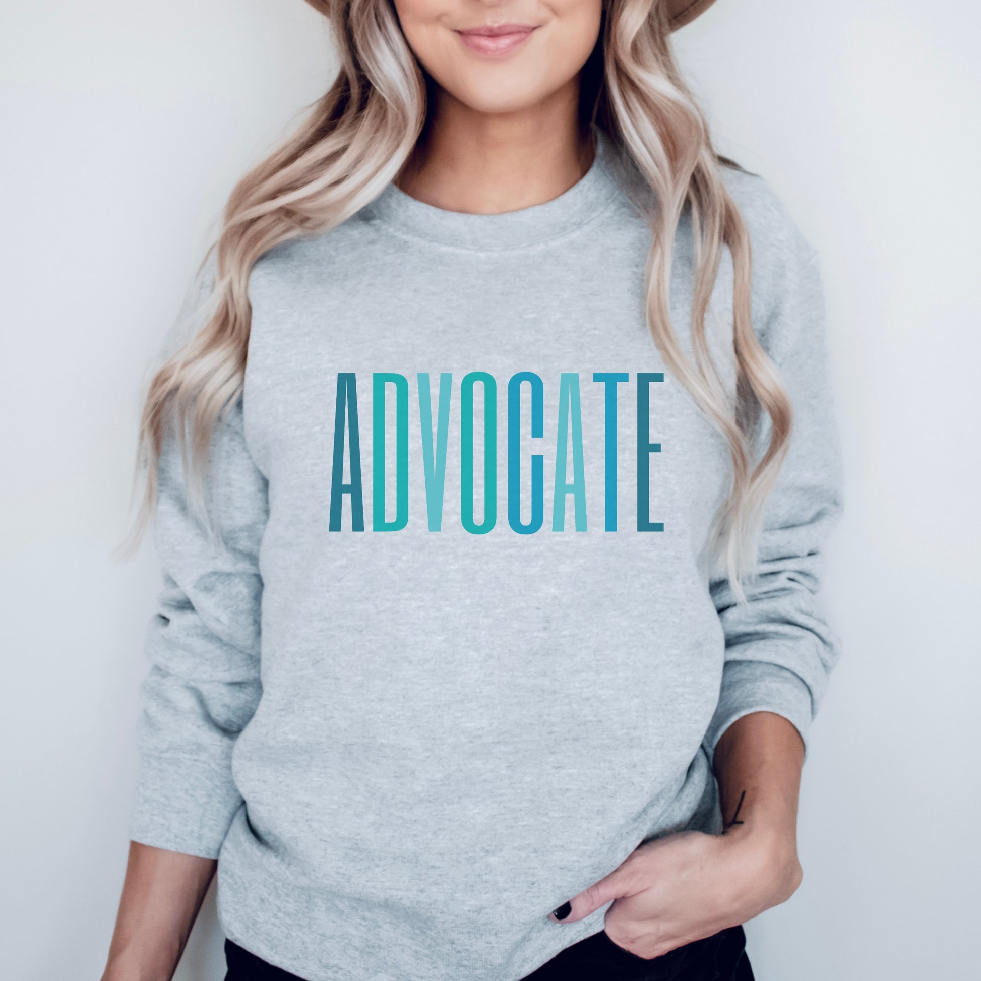 The front of the sweatshirt proudly displays the word ADVOCATE in a bold and eye catching font in varying shades of blue which is the color of child advocacy. It is a wearable symbol of your dedication to a world where all children are loved, cherished, and protected.