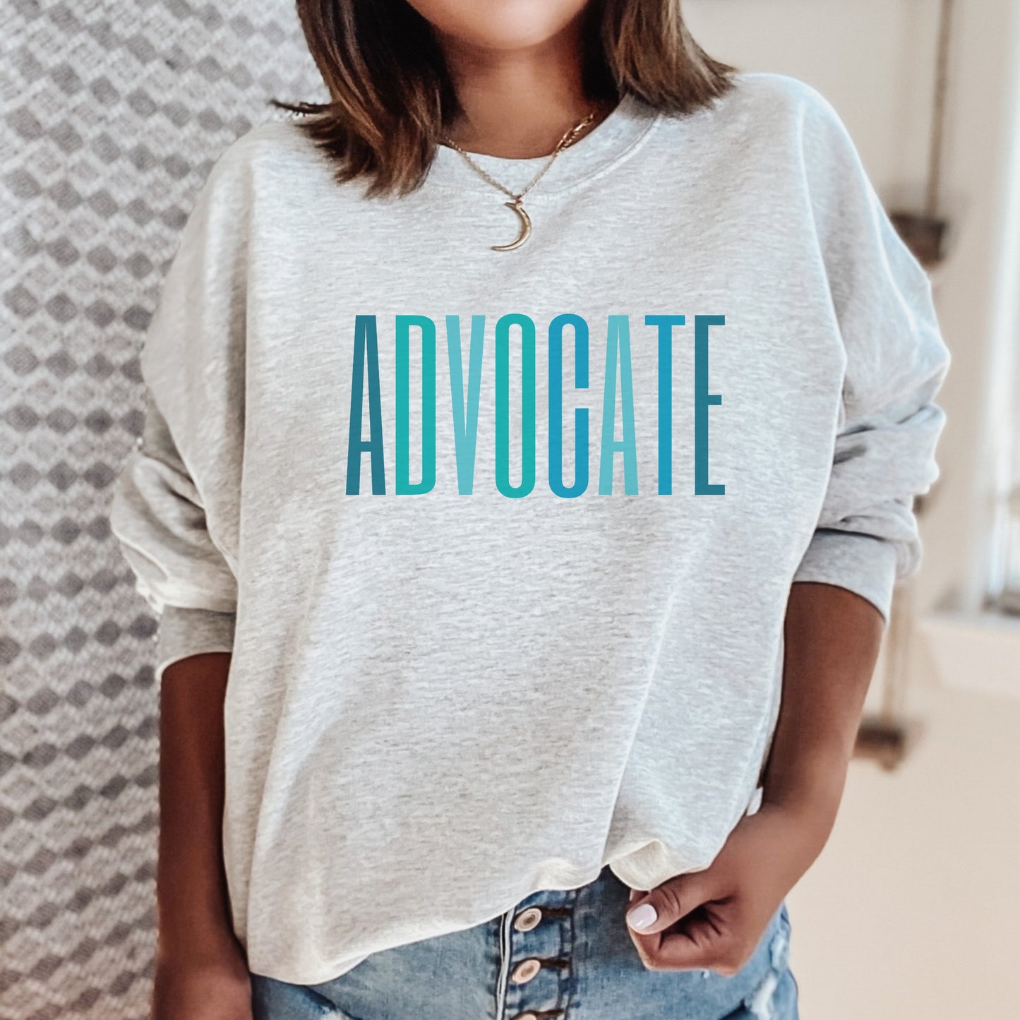 The front of the sweatshirt proudly displays the word ADVOCATE in a bold and eye catching font in varying shades of blue which is the color of child advocacy. It is a wearable symbol of your dedication to a world where all children are loved, cherished, and protected.