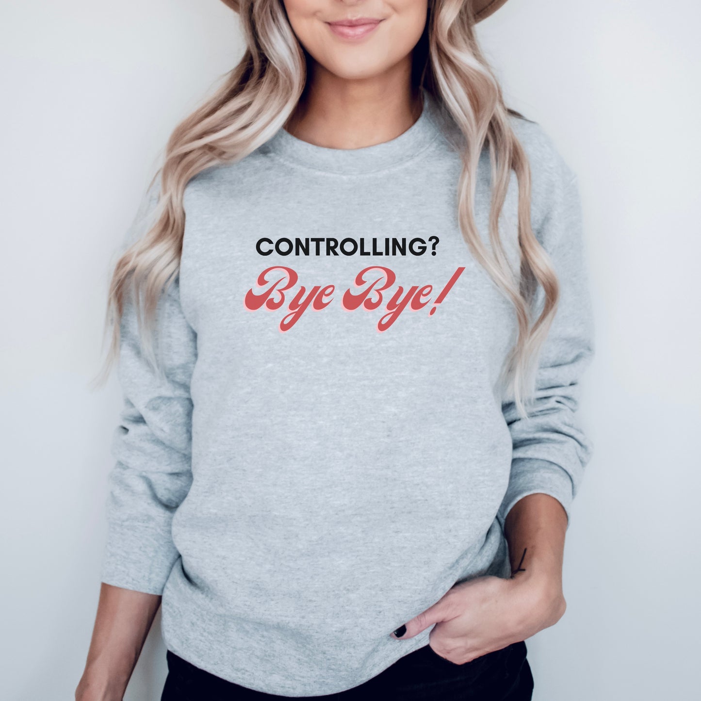 The front of the sweatshirt proudly displays the phrase "Controlling? Bye Bye!" in a bold and eye-catching font. This message serves as a reminder that love is not controlling. Tailored for domestic violence and teen dating violence advocates.