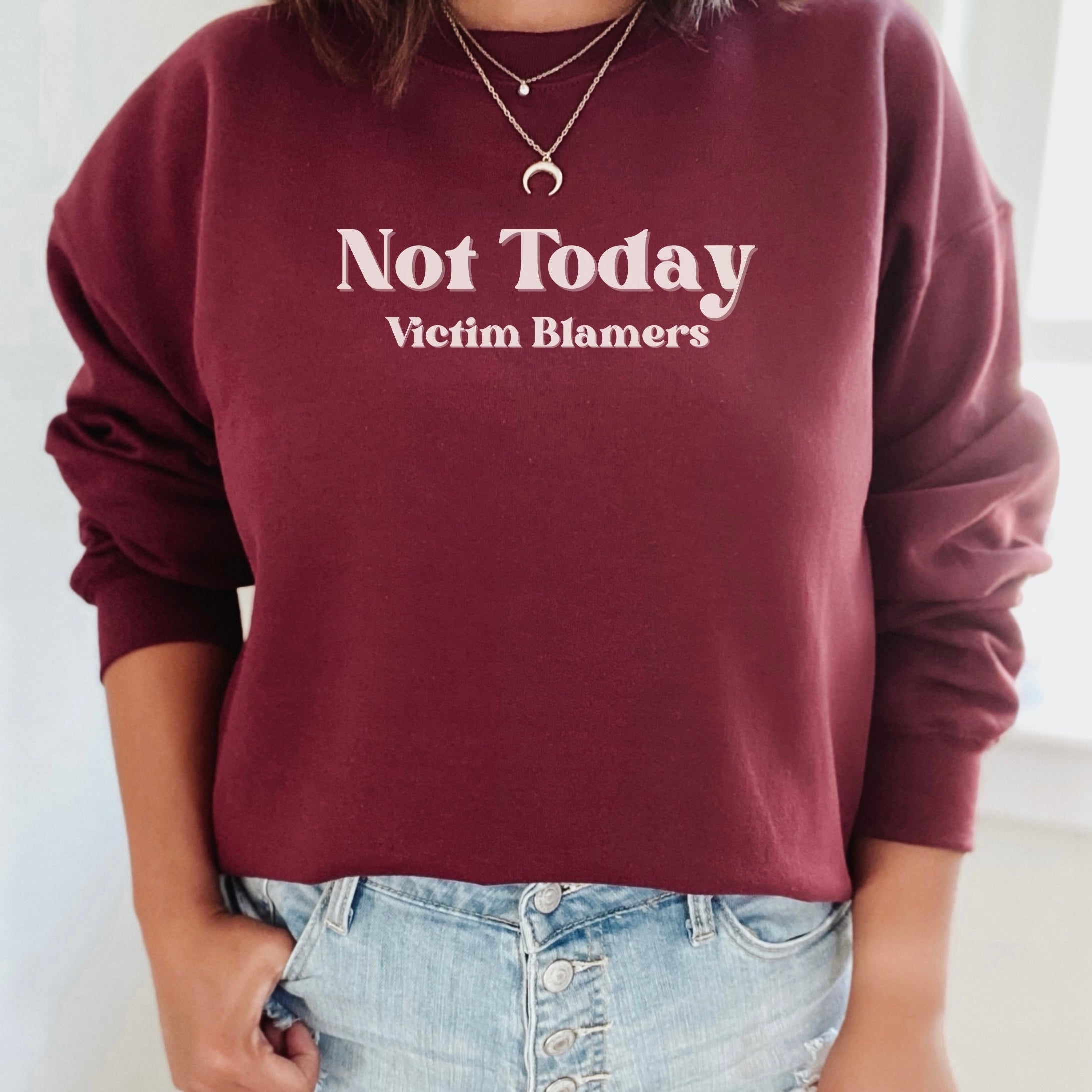 The front of the Maroon sweatshirt proudly displays the phrase "Not Today Victim Blamers" in a white bold and eye-catching font. This message serves as a reminder that we reject victim-blaming and support those who have faced injustice.