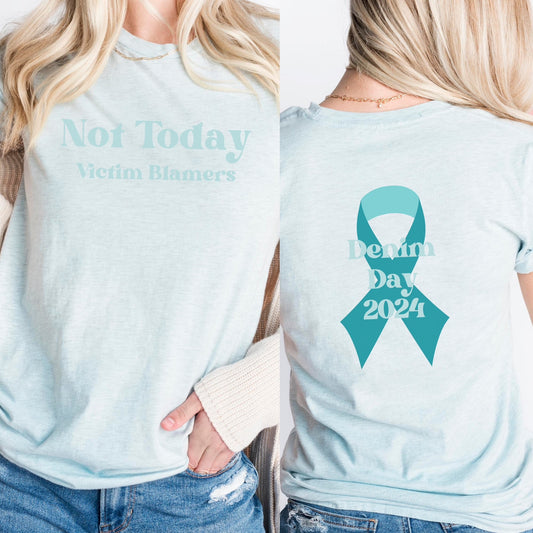 The front of the t-shirt in bold teal letters declare "Not Today Victim Blamers," challenging the harmful narratives survivors often face. The back of the shirt features the SAAM teal awareness ribbon with the words "Why I Wear Denim 2024" making the wearer a walking ambassador for awareness and change. Perfect For Sexual Assault Awareness Month and Denim Day.