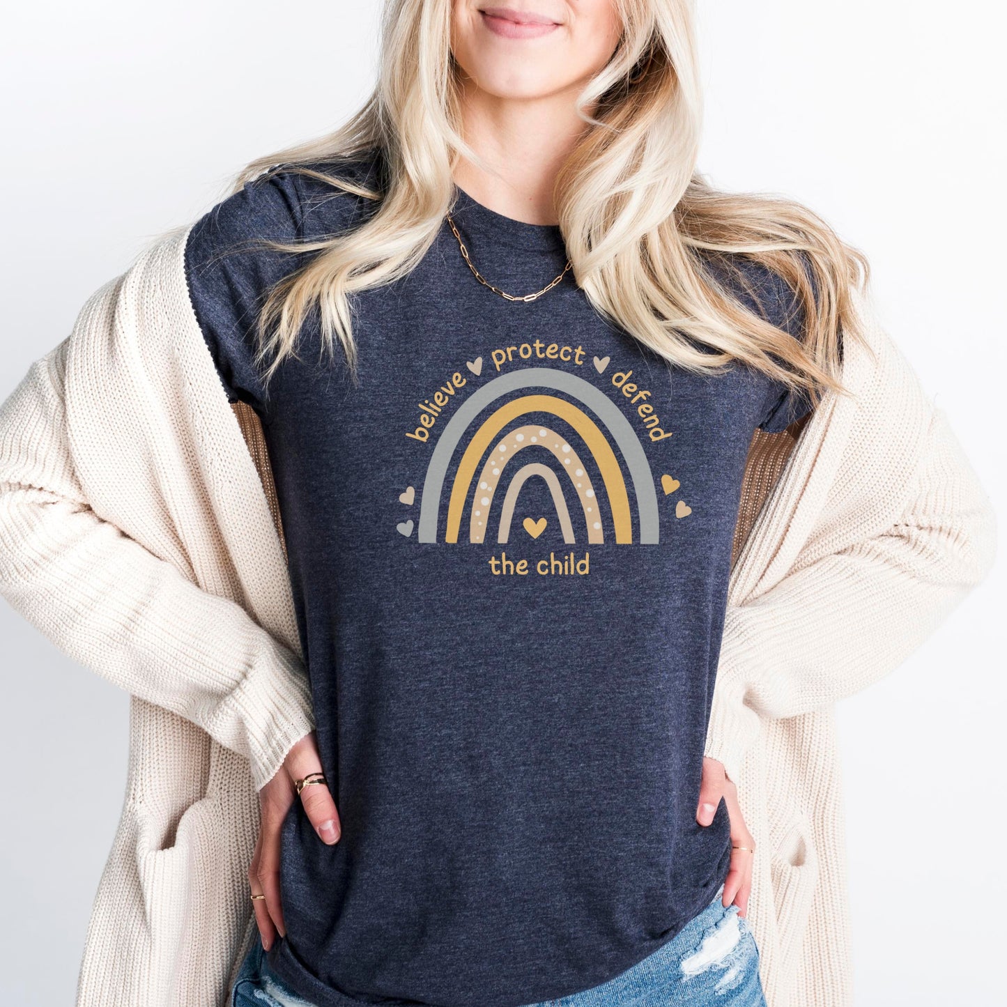 The front of the tee displays a boho rainbow with the phrase Believe Protect Defend The Child. A powerful message that underscores the importance of safeguarding children's rights and well being. Perfect for child advocates and Child Abuse Awareness and Prevention Month (CAAPM)