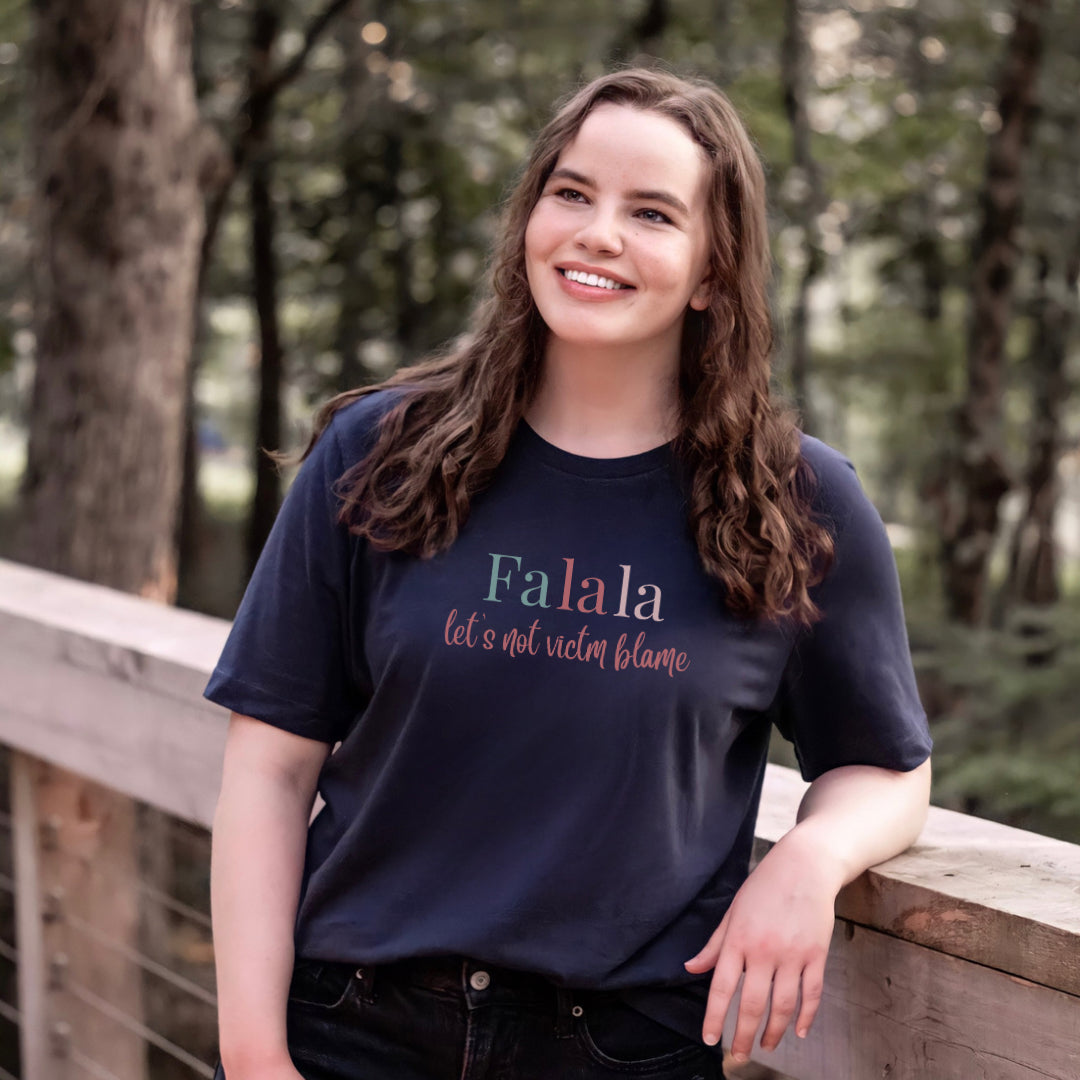 Empowerment-themed holiday T-shirt with festive trending colors design and the powerful statement 'Fa la la, Let's Not Victim Blame.' Ideal for advocates and survivors of abuse, this tee promotes empathy and awareness during the holiday season.