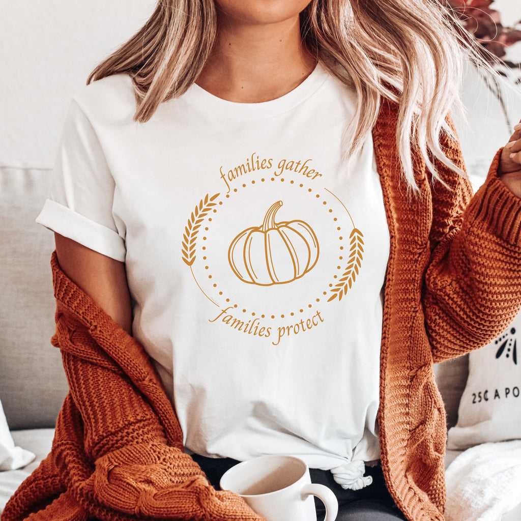 Adorned with a heartwarming autumn-fall harvest pumpkin graphic and the inspiring message Families Gather, Families Protect, this White T-shirt stands as a testament to the unwavering support and protection families should offer to survivors.